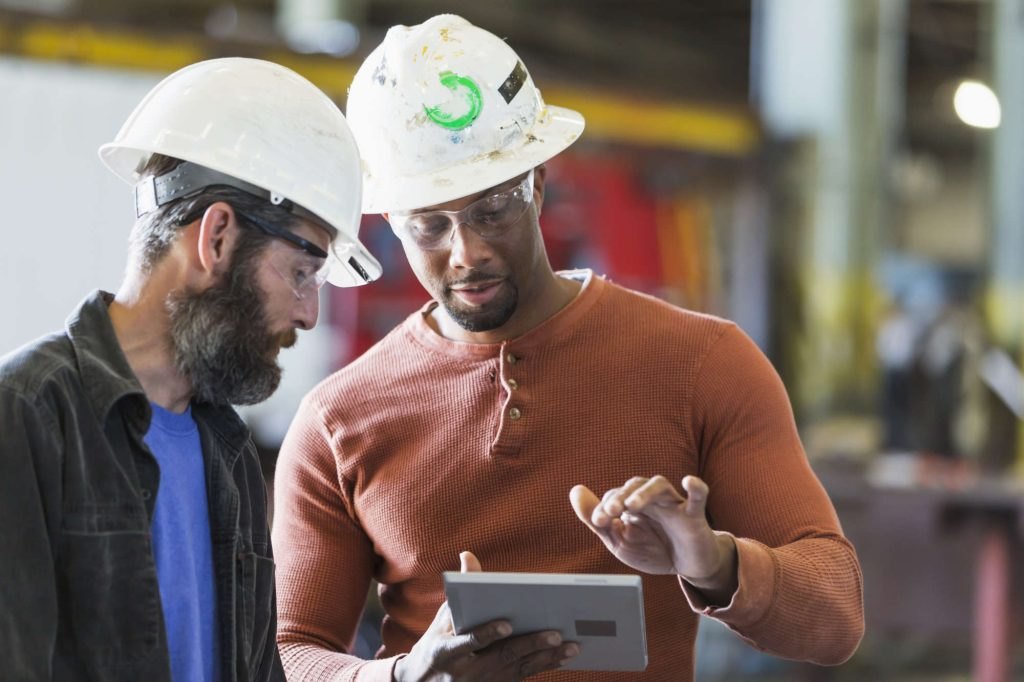 Two tradesmen reviewing job details on a tablet